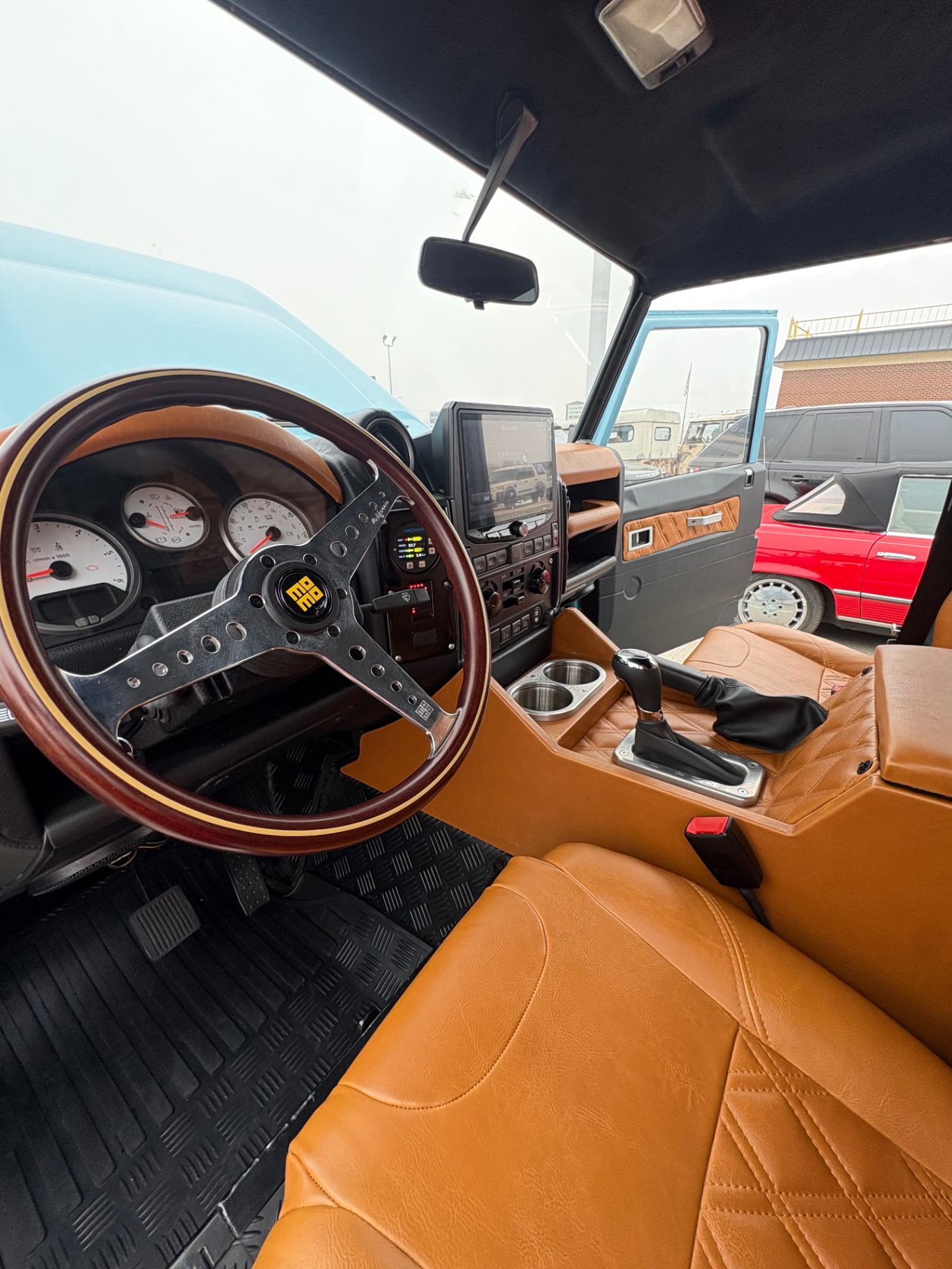 Finished sky blue Defender interior with wood-rim MOMO wheel and tan leather