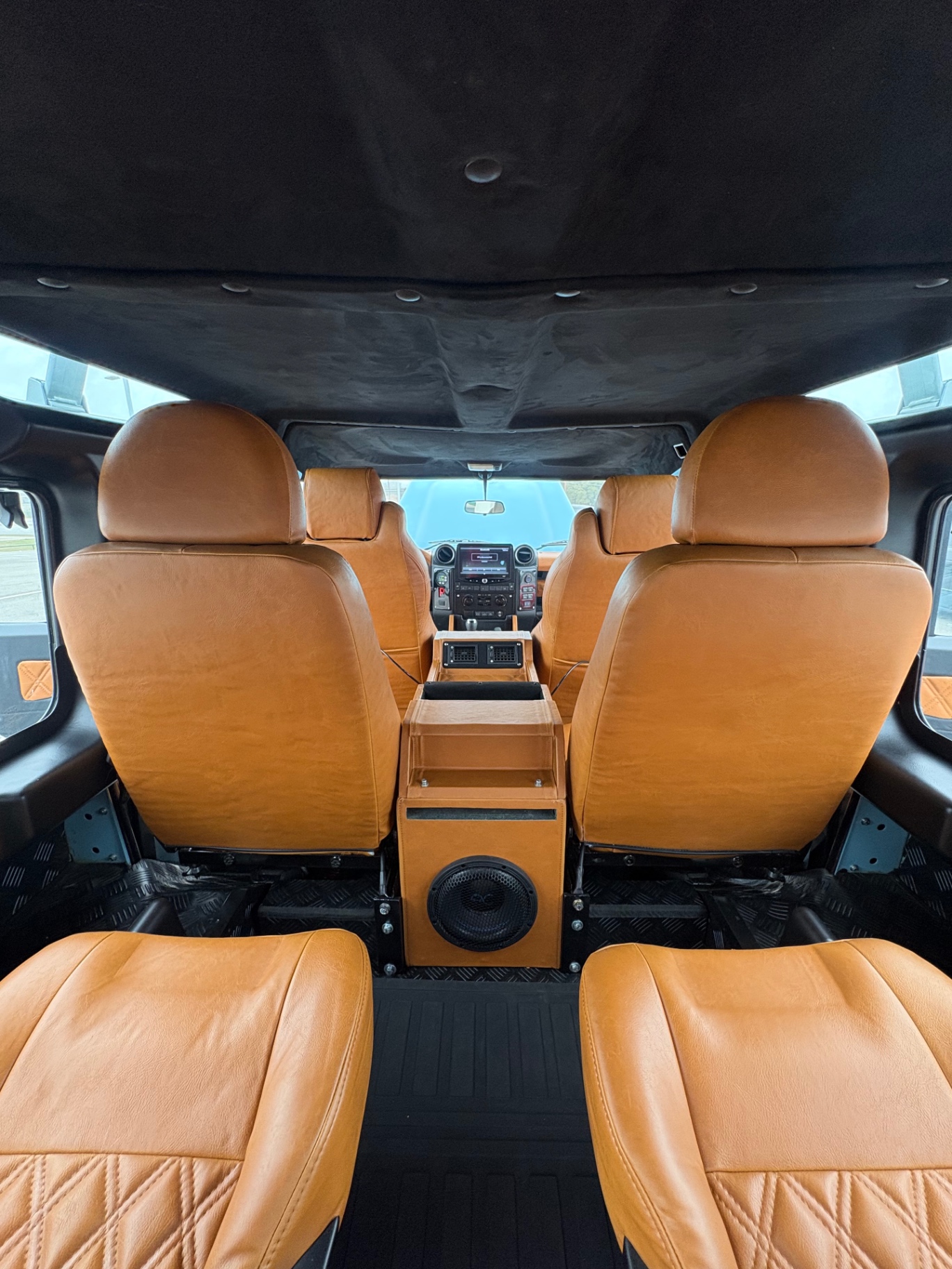 Rear cabin view of Defender with tan leather seats and subwoofer console