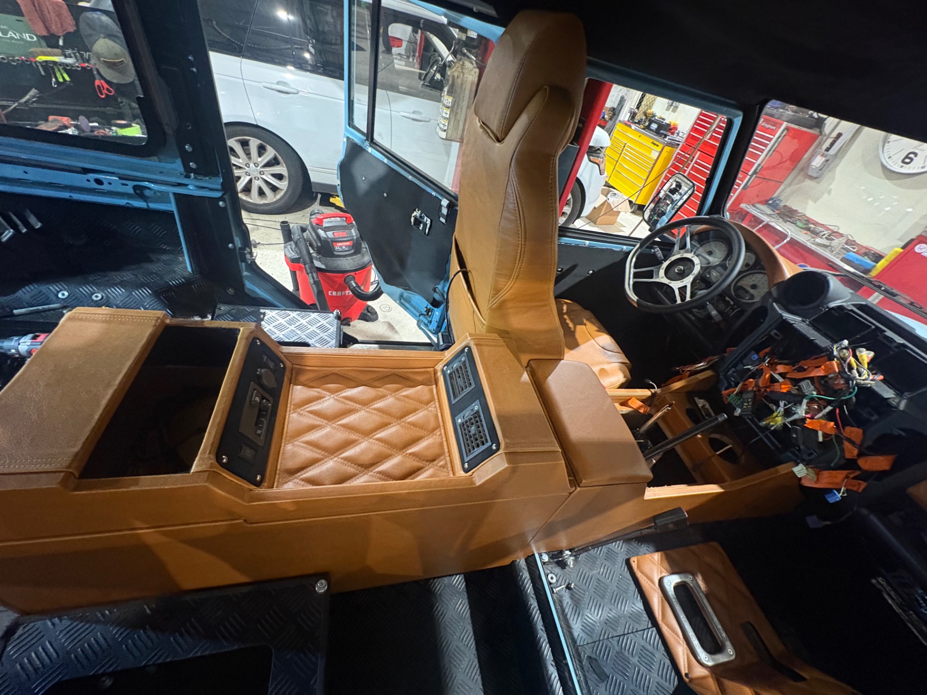 Diamond-stitched tan console with vents in a sky blue Defender