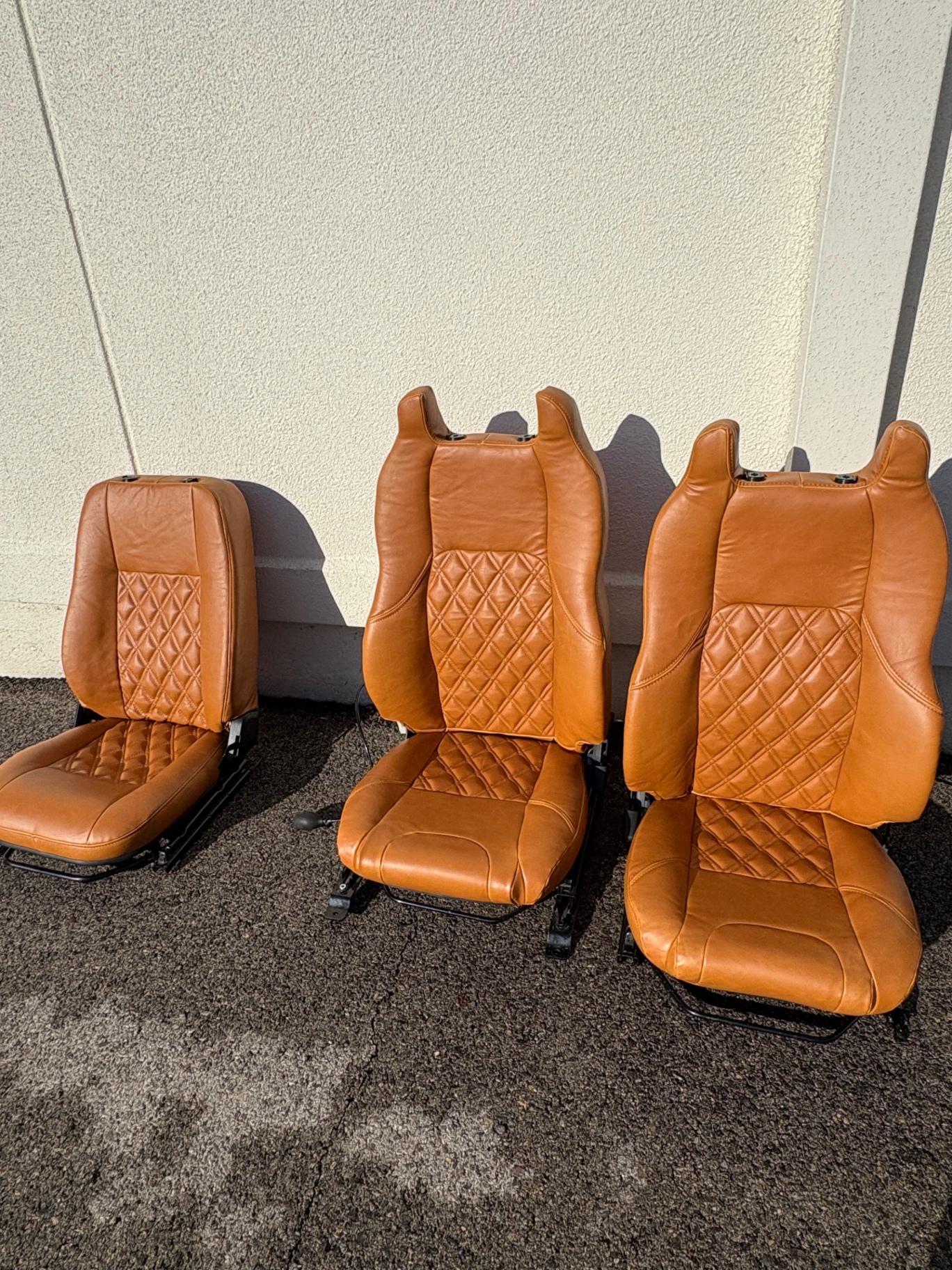 Tan diamond-stitched leather Defender seats lined up in the sun
