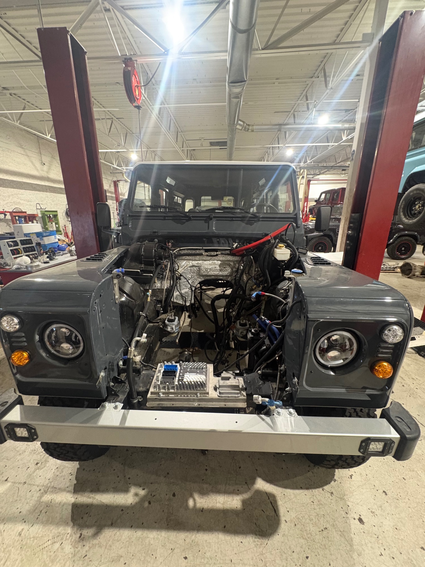 Front view of a grey Defender with the engine bay open during a conversion