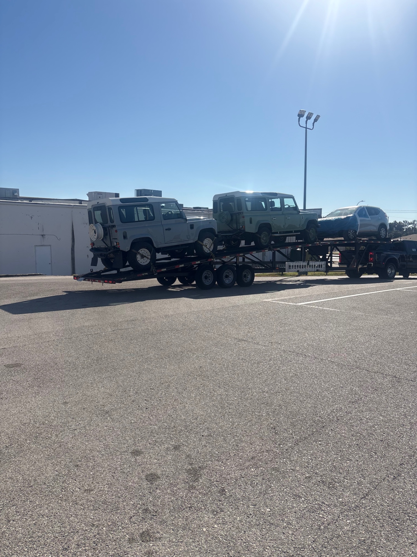 Custom Defenders loaded on a transport trailer leaving the Fort Worth Rover shop