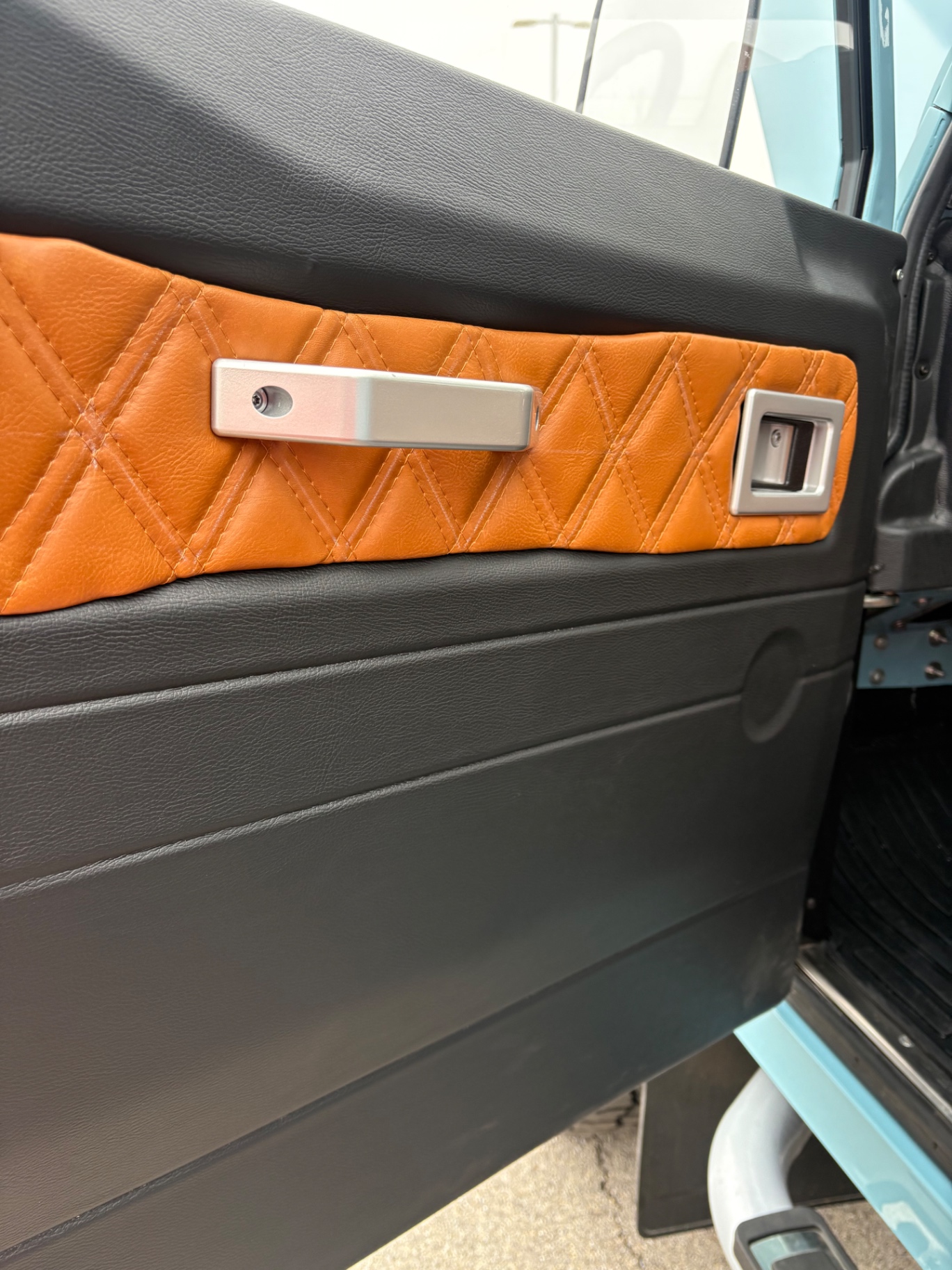 Custom two-tone black and orange diamond-stitched Defender door card