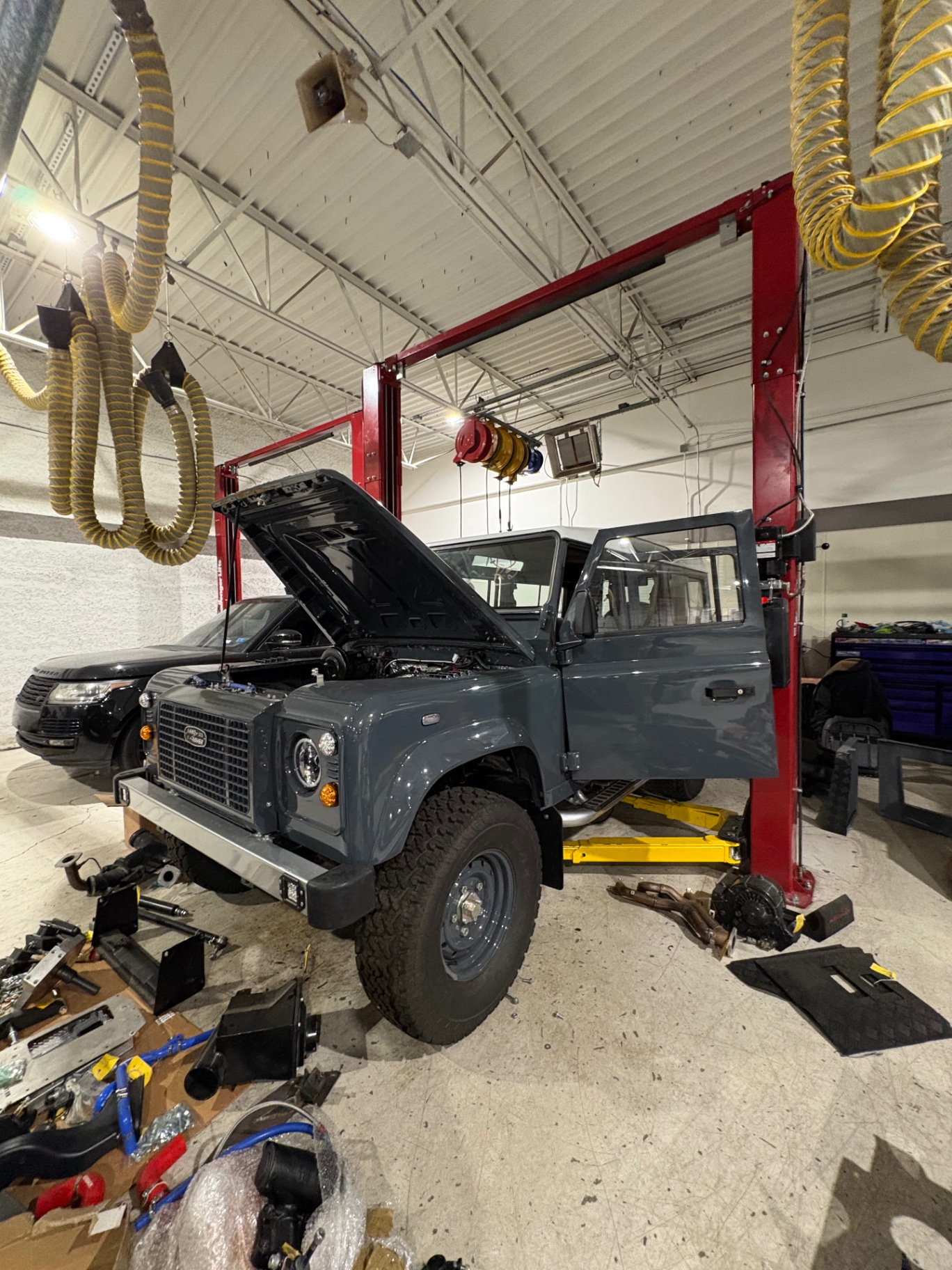 Slate grey Defender 110 on a two-post lift during a full mechanical build
