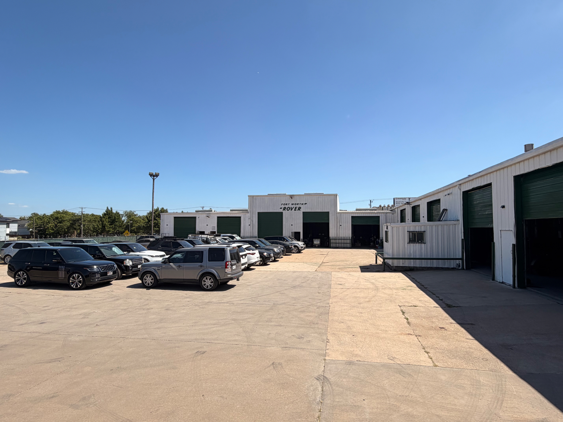 The Original Fort Worth Rover facility exterior at 700 Missouri Ave with client Land Rovers parked in front of the service bays