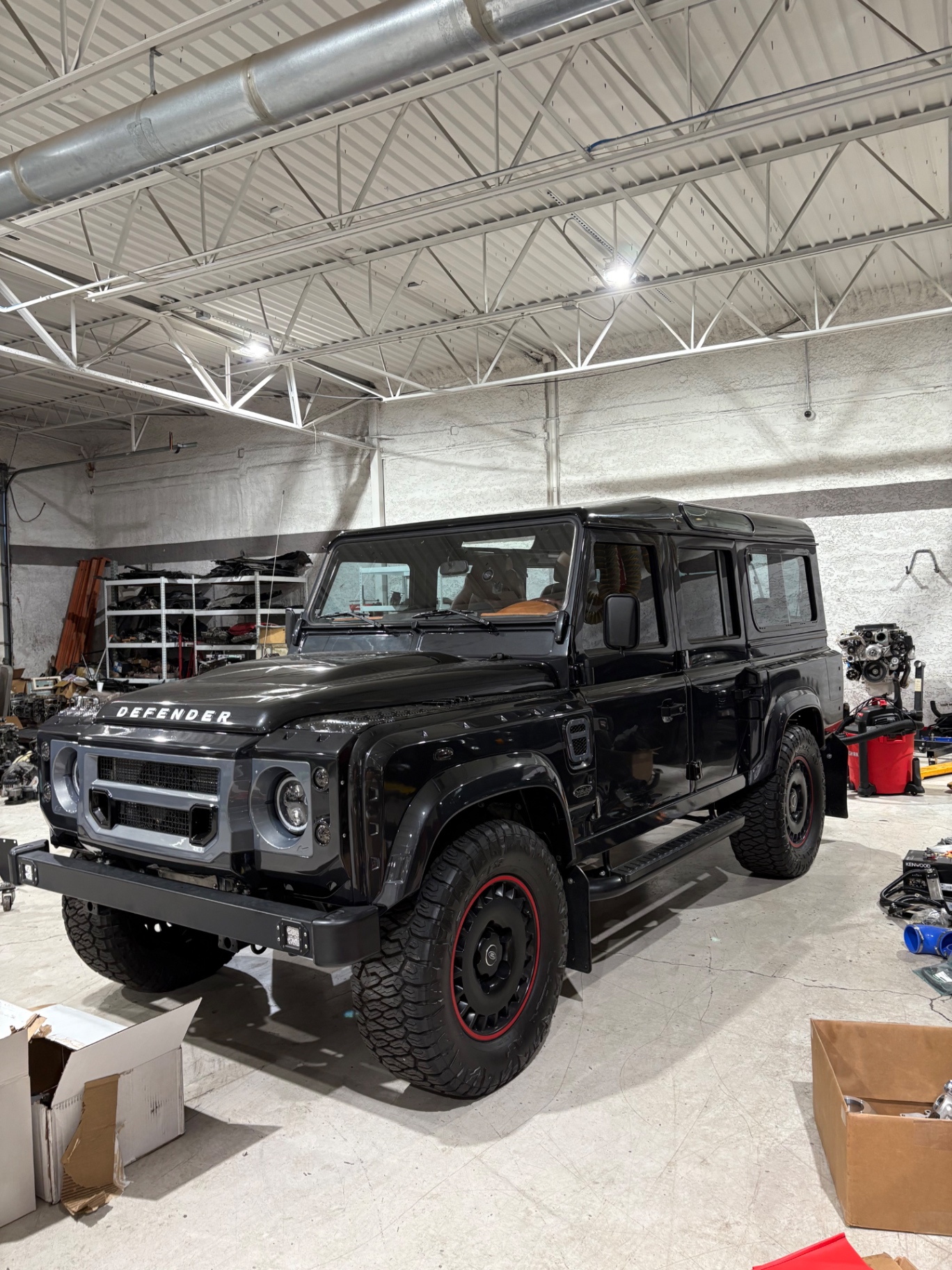 Blacked-out Defender 110 with red pinstripe wheels and modernized front grille